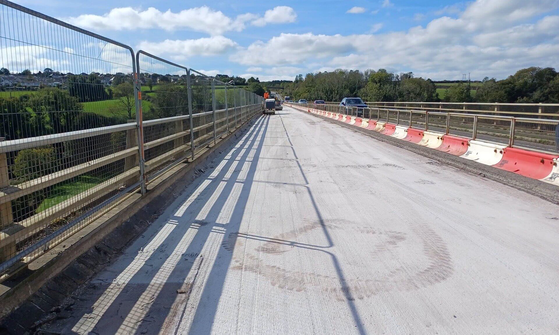 Bare concrete bridge deck on the Camel Viaduct at Wadebridge with safety fencing and traffic passing on the other side