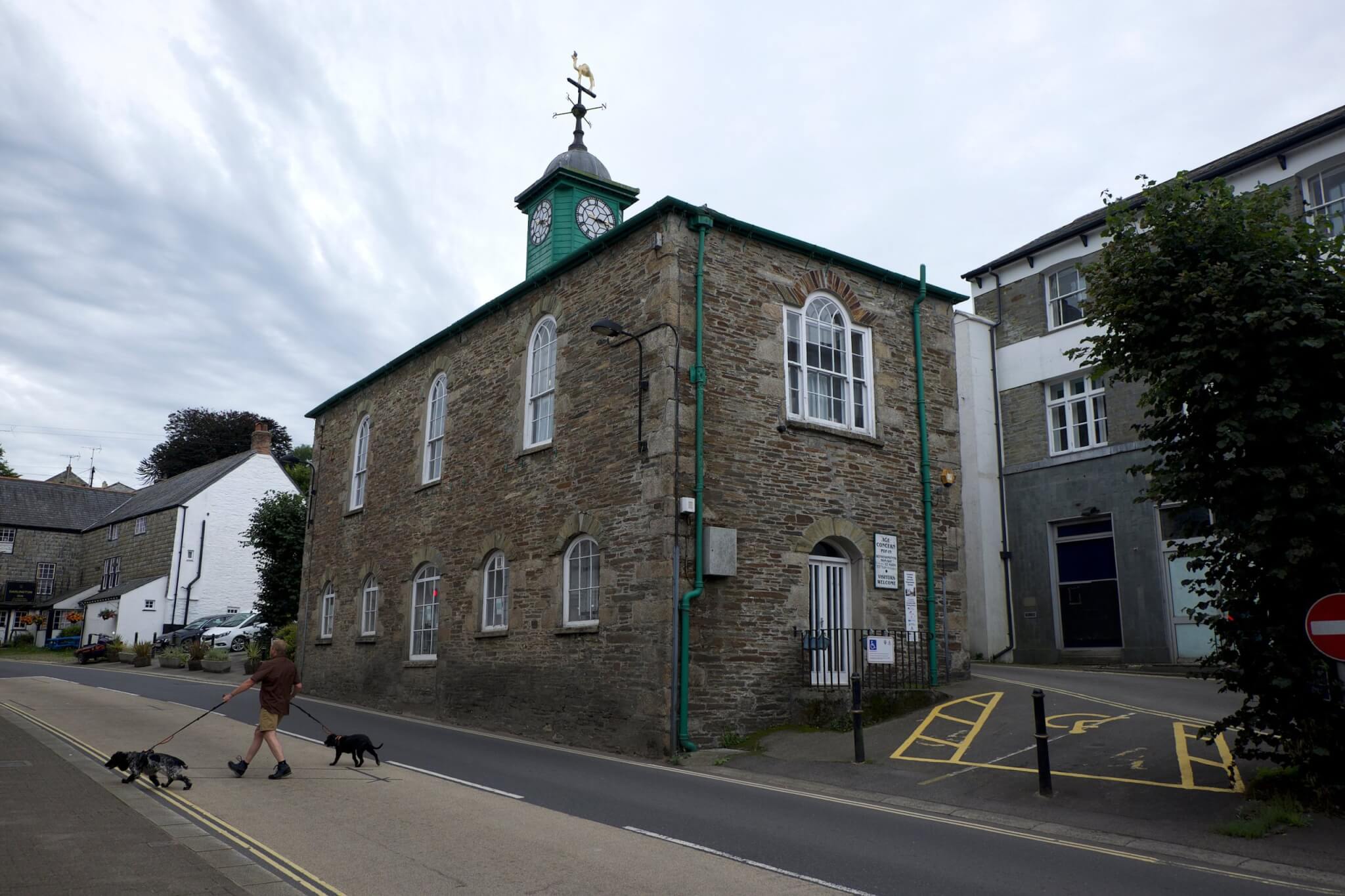 Stone building with a green clock tower and weathervane in Camelford