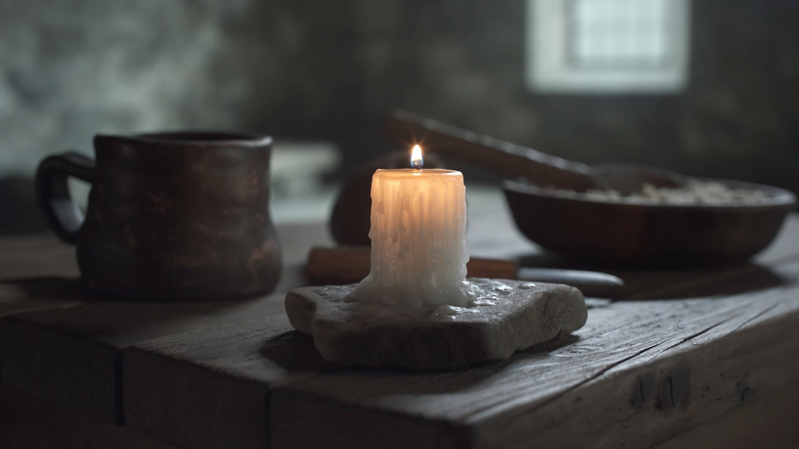 A lit candle on a wooden table in a dim room during a power cut