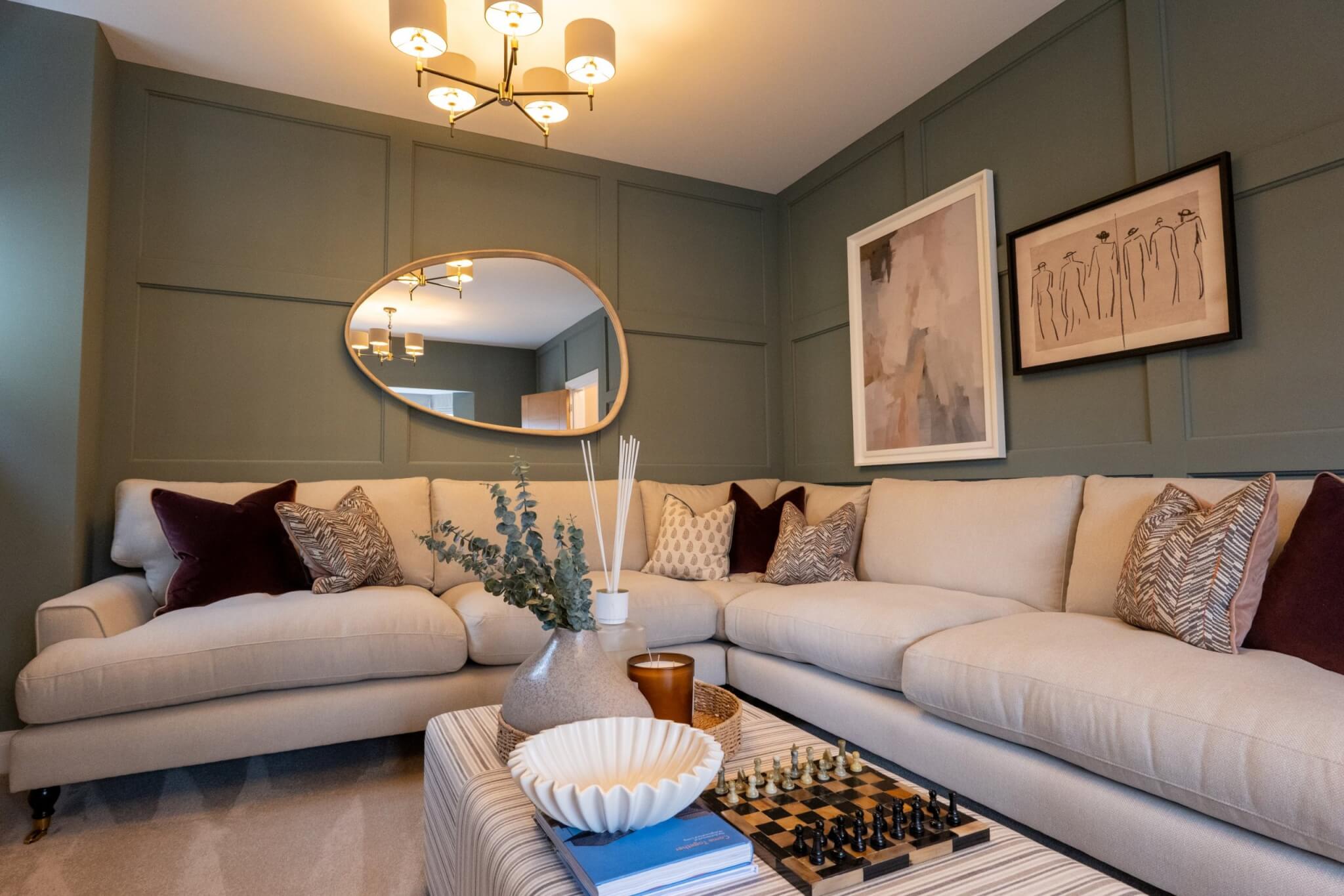 Living room with panelled green walls and a cream corner sofa in a Cavanna Homes showhome
