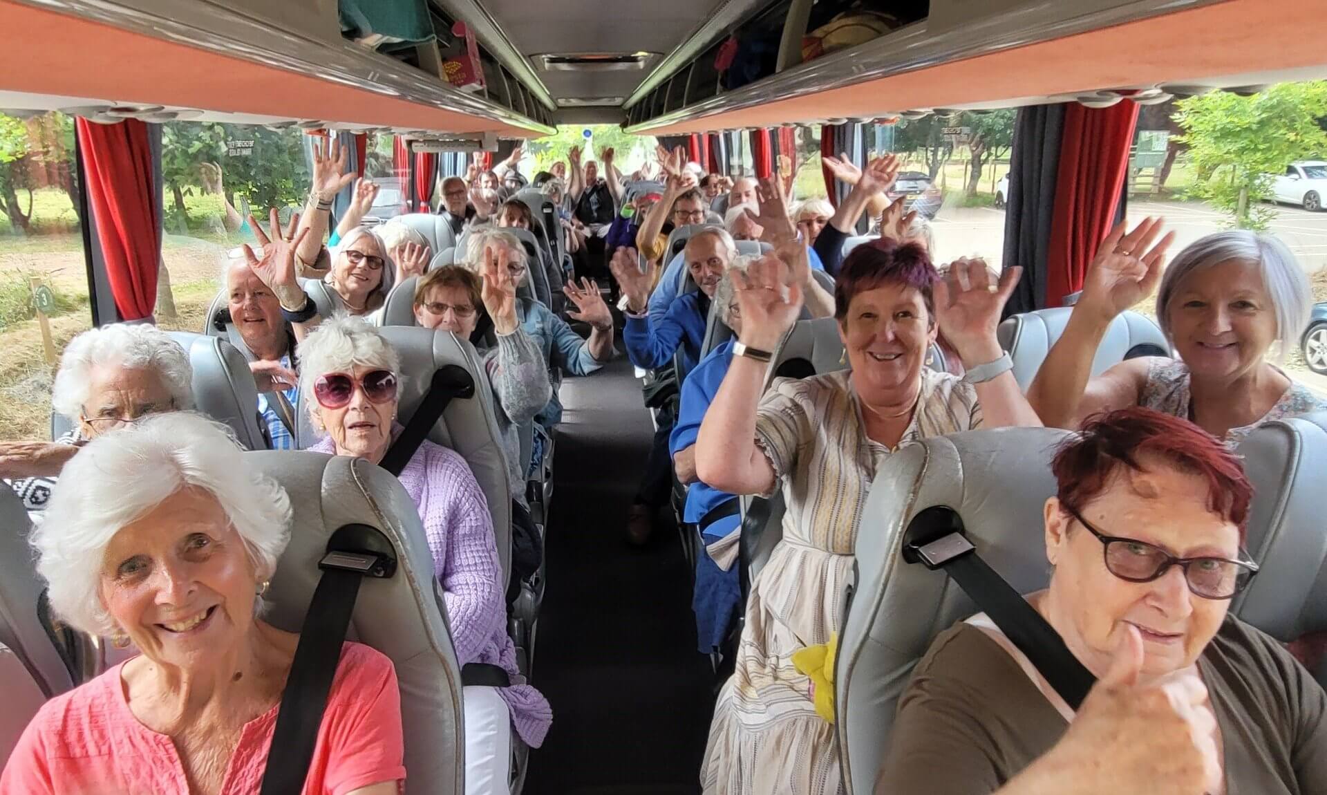 Smiling passengers waving from their seats on a coach