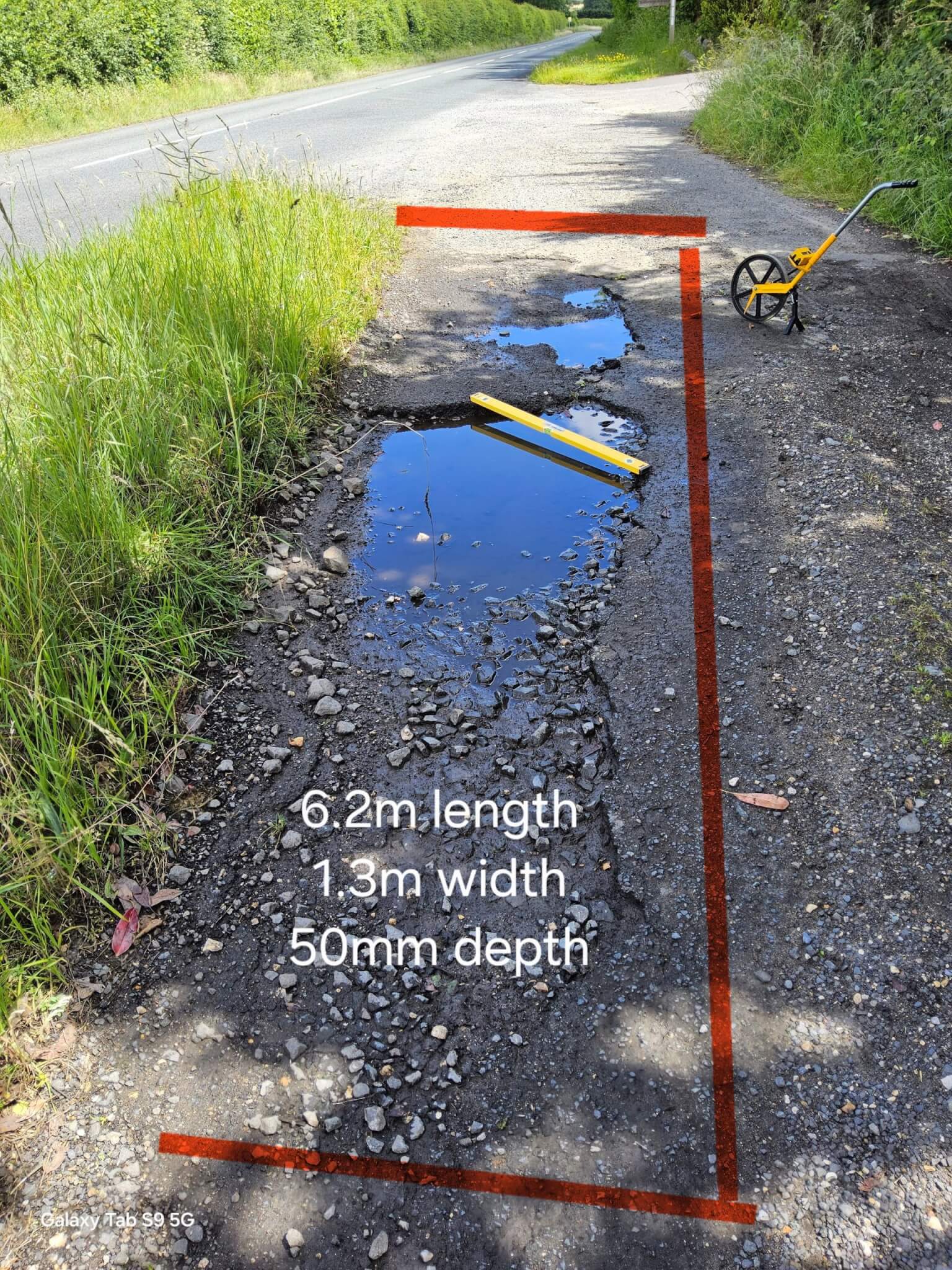 A large water-filled pothole marked out for repair