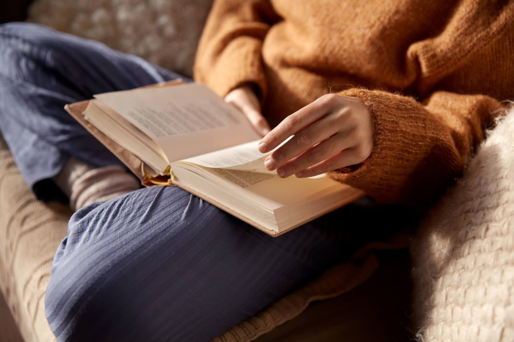 A person reading an open book on their lap