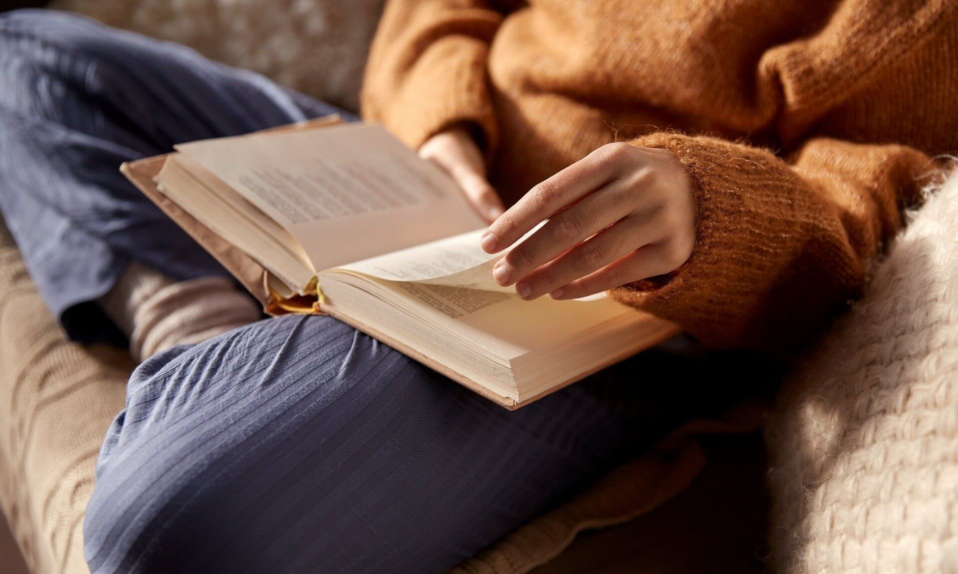 A person reading an open book on their lap