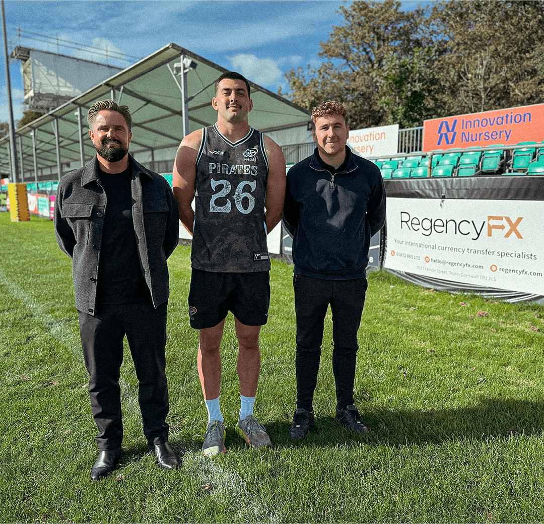 Josh Radcliffe of the Cornish Pirates with Andy Dyer and Sam Harratt pitchside by a Regency FX banner