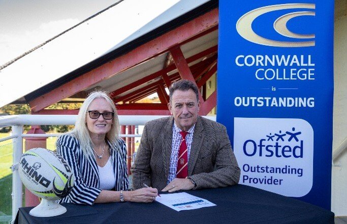 The partnership agreement being signed beside a Cornwall College banner
