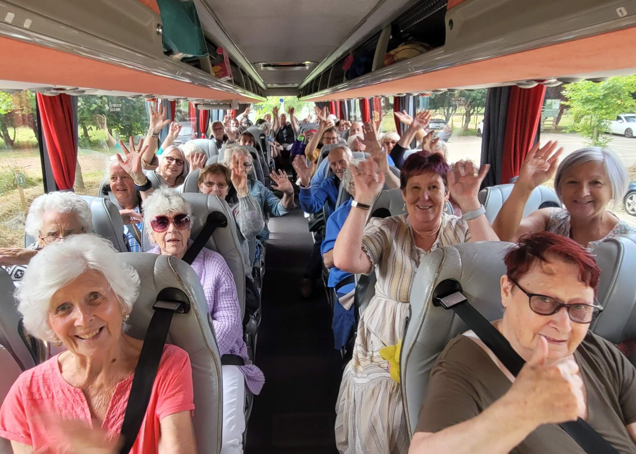 Smiling passengers waving from their seats on a coach