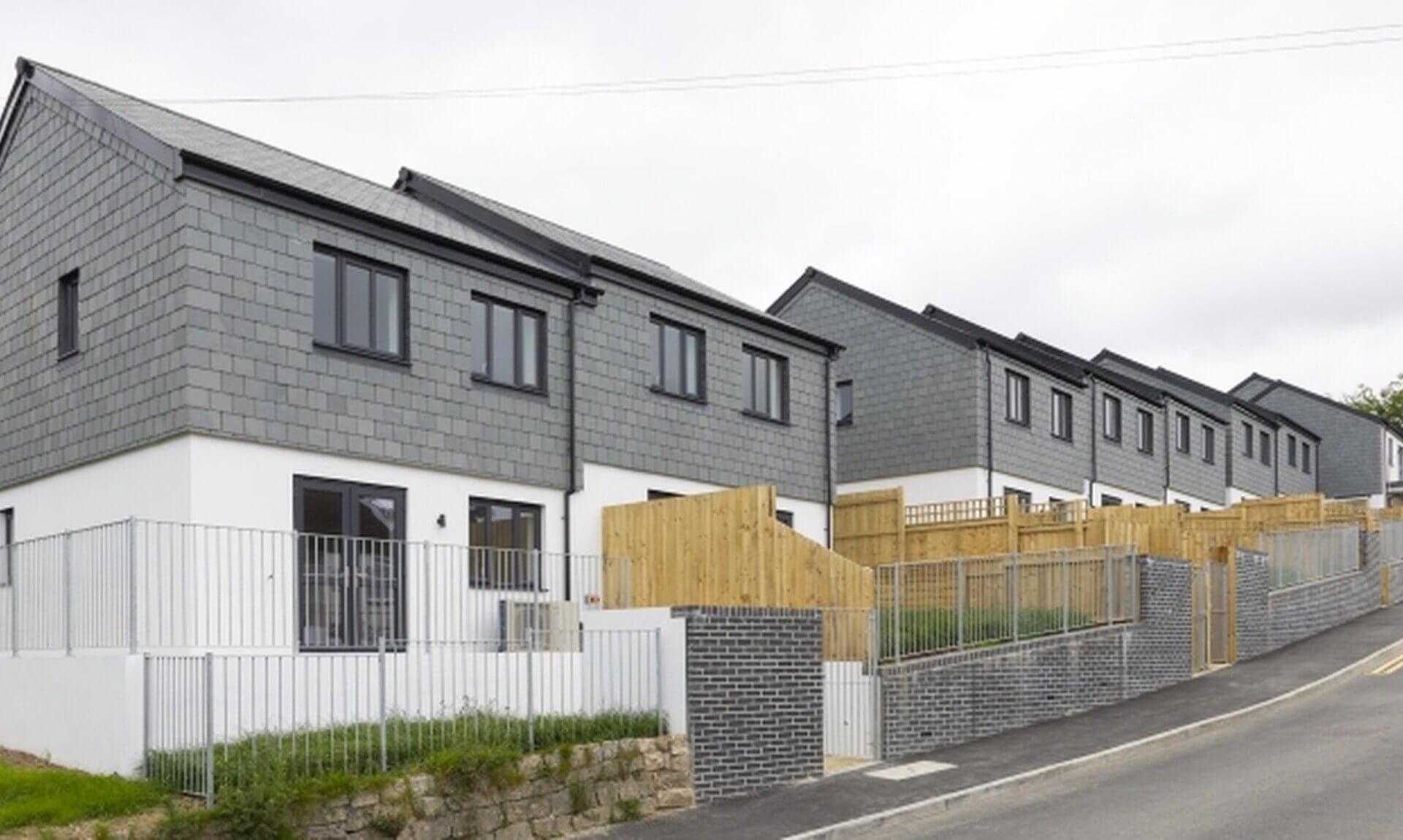 Row of new slate-clad terraced homes on a hillside street