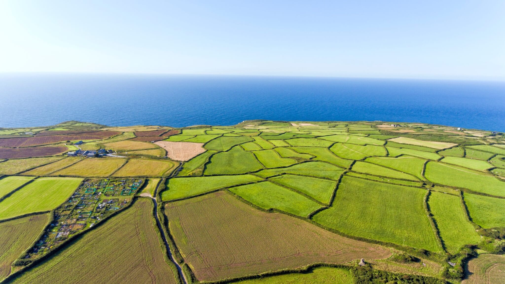 Aerial view of patchwork farm fields running to the sea on the Cornish coast