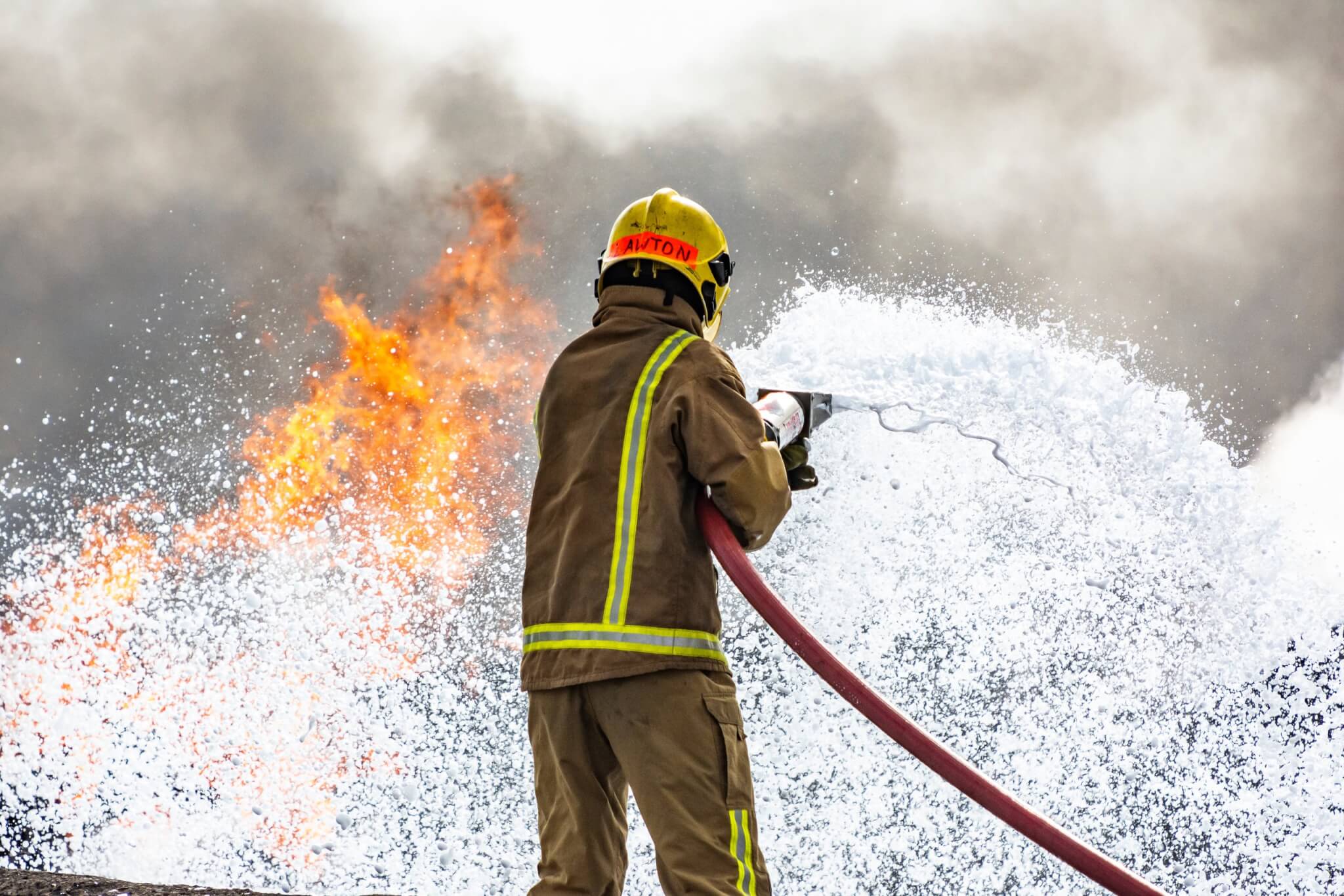 Firefighter tackling a blaze with a foam jet