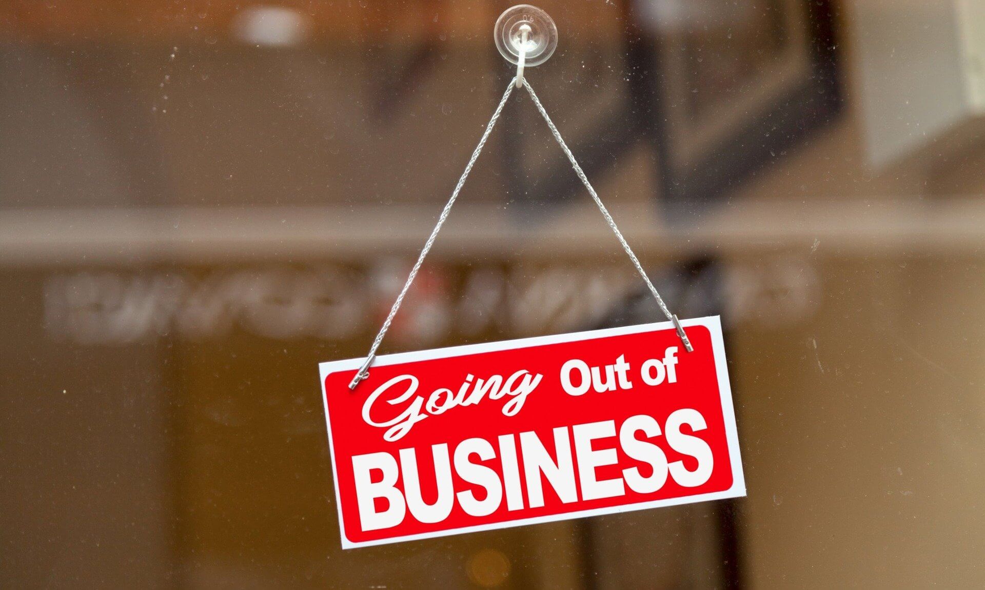 A red Going Out of Business sign hanging in a shop window