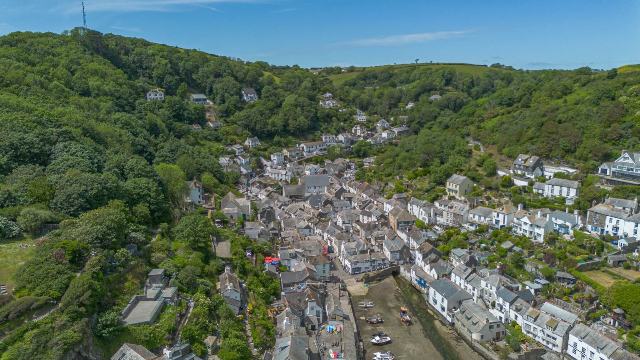 Aerial view of a Cornish harbour village in a wooded valley