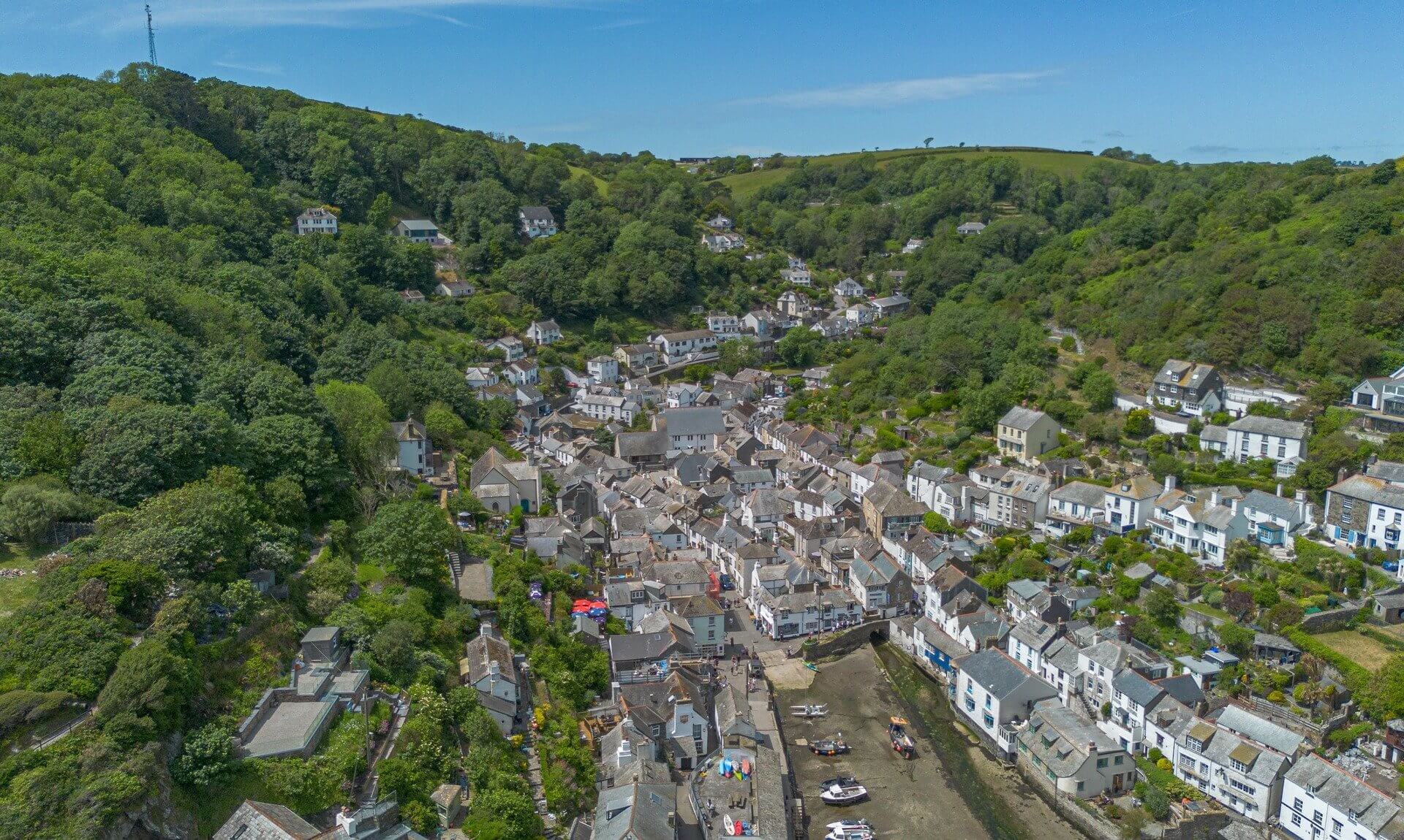 Aerial view of a Cornish harbour village in a wooded valley
