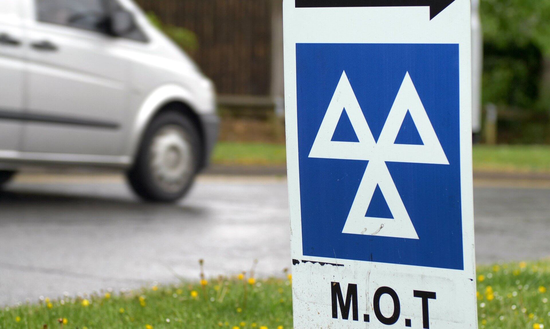 MOT test centre sign beside a road with a van passing