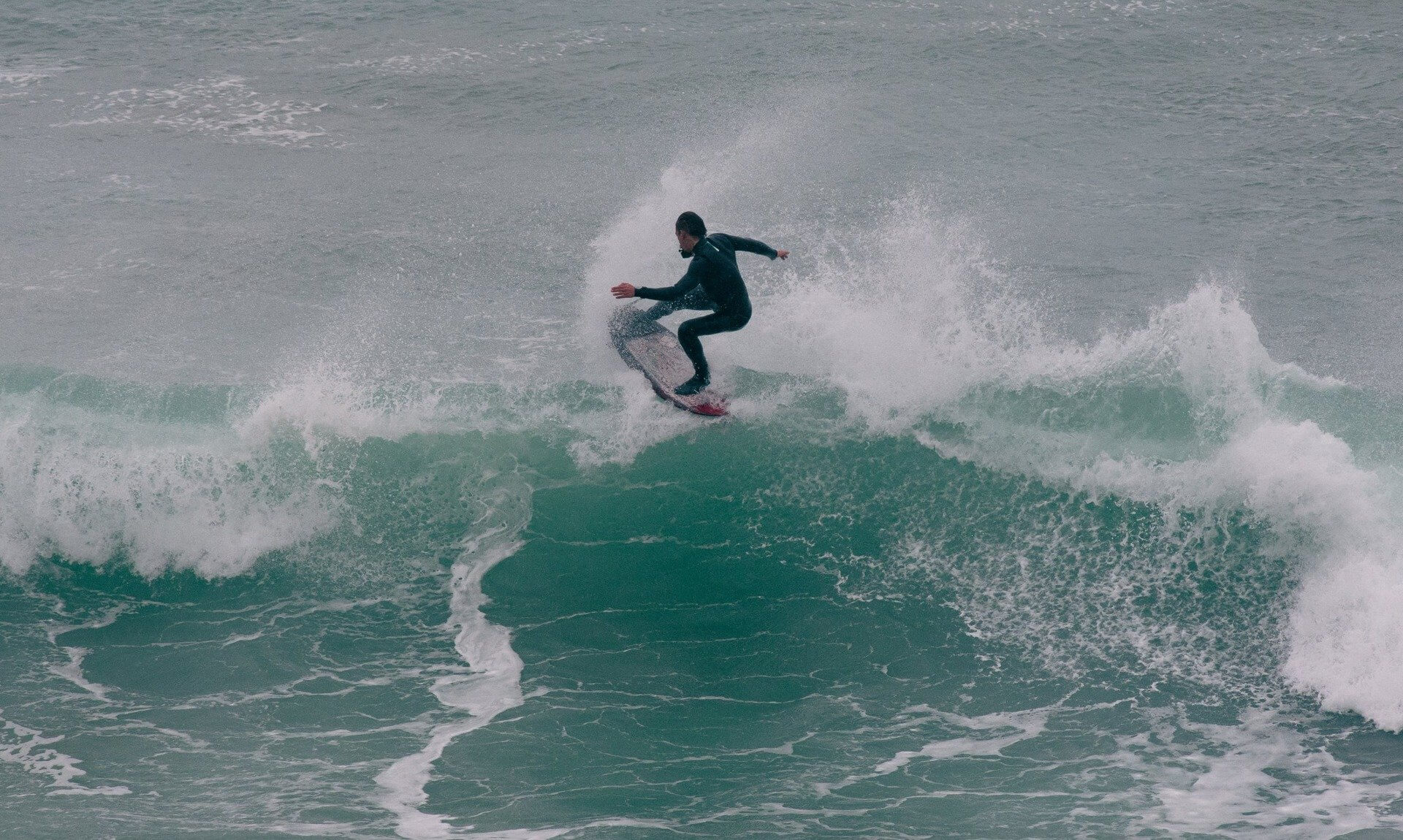Surfer carving a wave off the Cornish coast