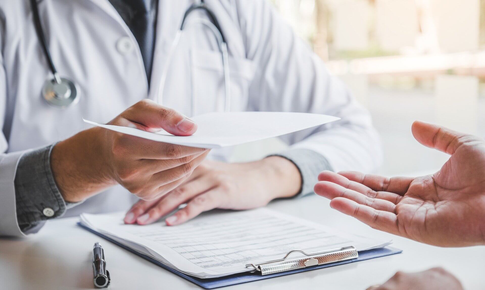 Doctor handing a prescription to a patient across a desk