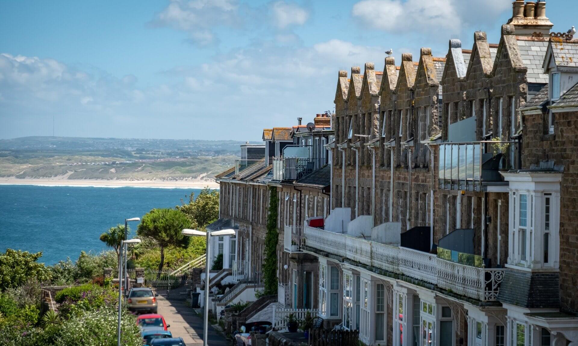Row of granite terraced houses overlooking the sea and sand dunes in Cornwall