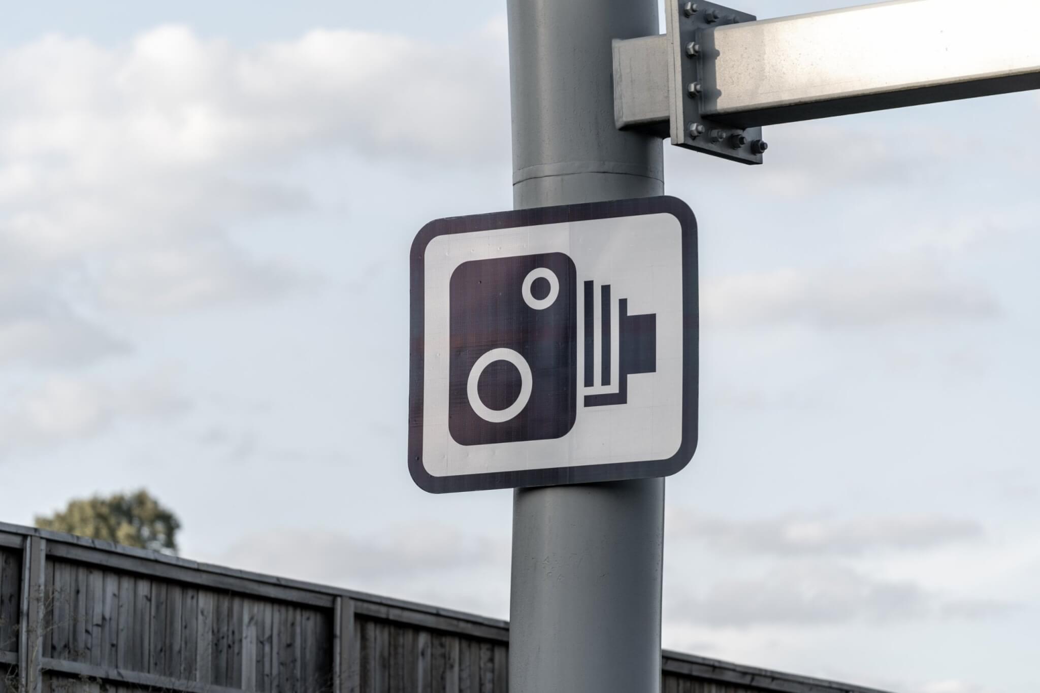 Speed camera warning sign on a roadside pole