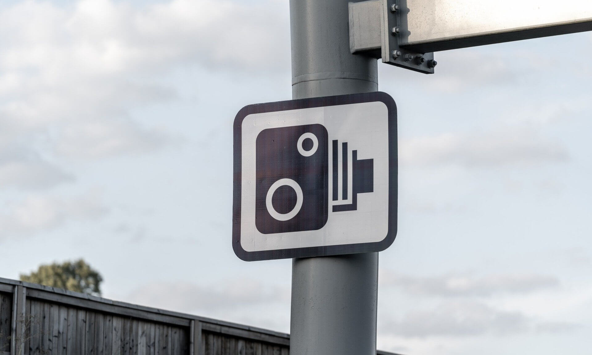 Speed camera warning sign on a roadside pole
