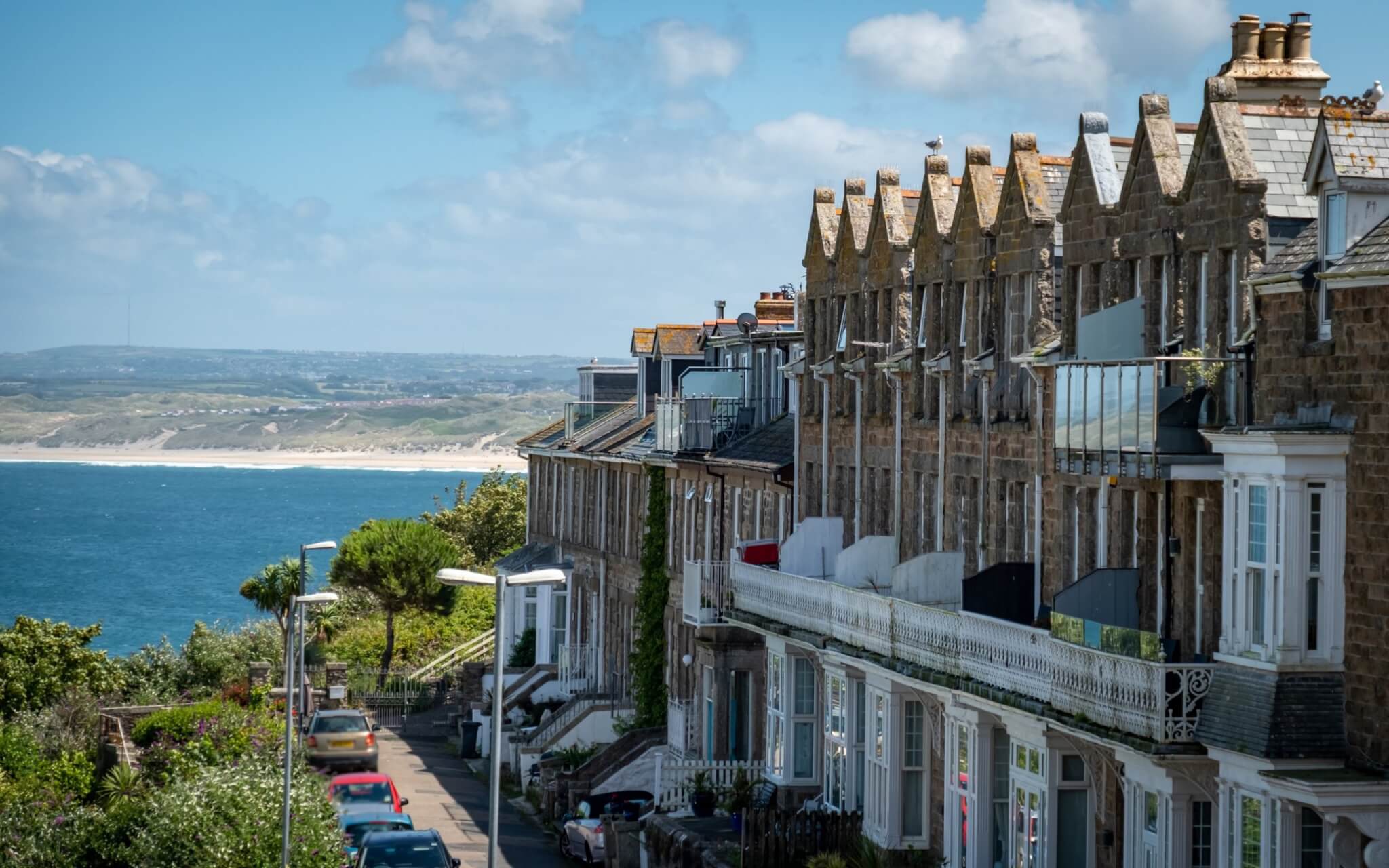 Row of granite terraced houses overlooking the sea and sand dunes in Cornwall