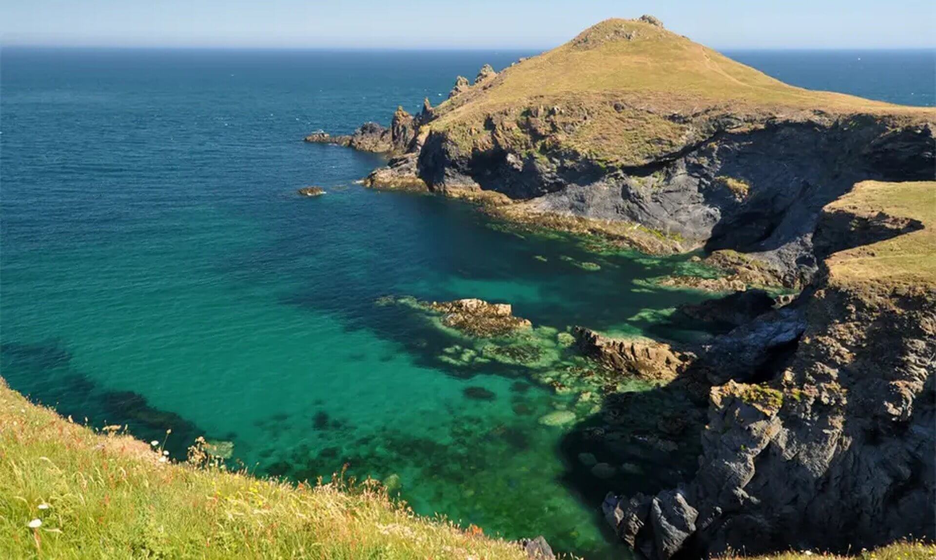 The Rumps headland above clear turquoise water near Polzeath