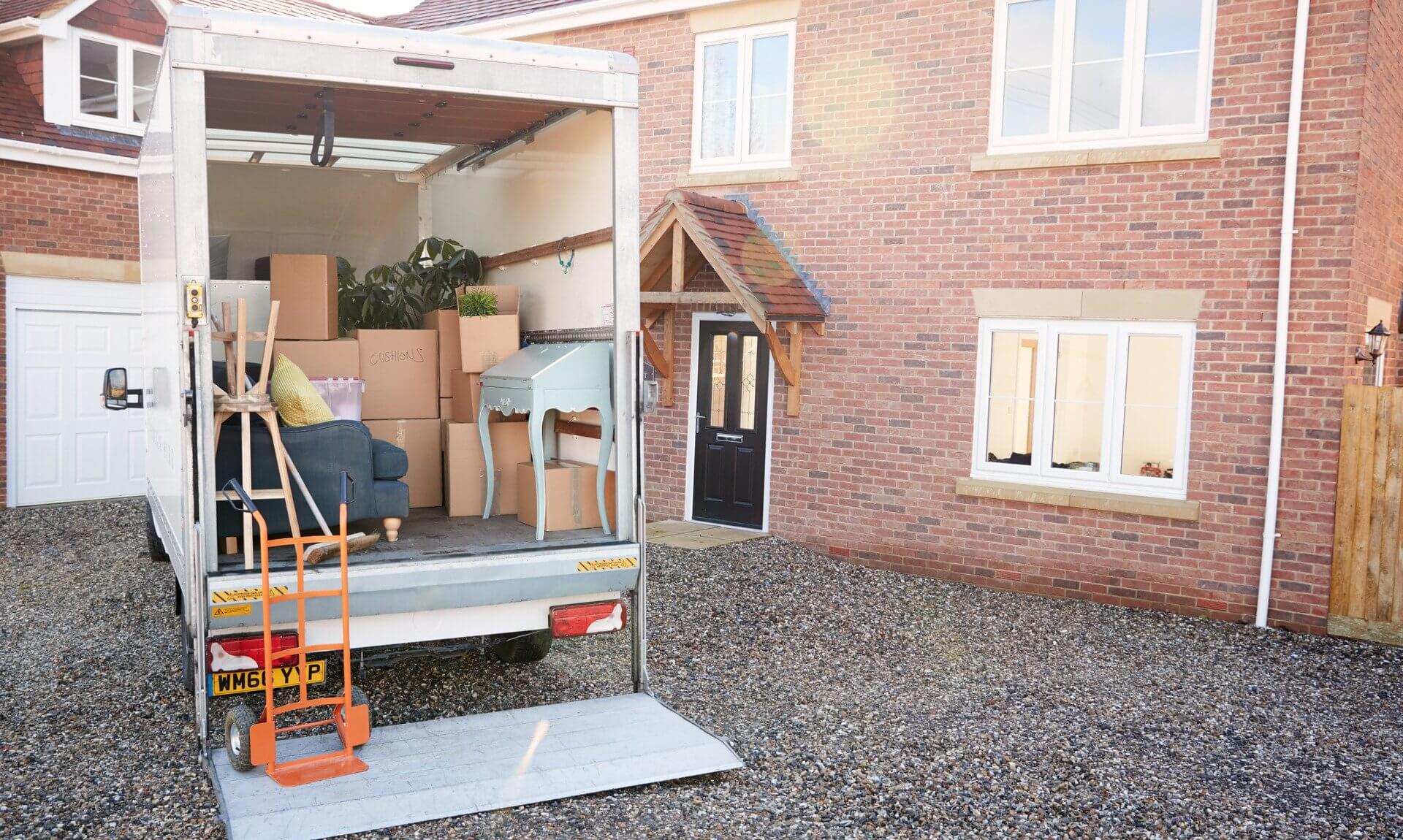 Removal van loaded with boxes and furniture outside a brick house
