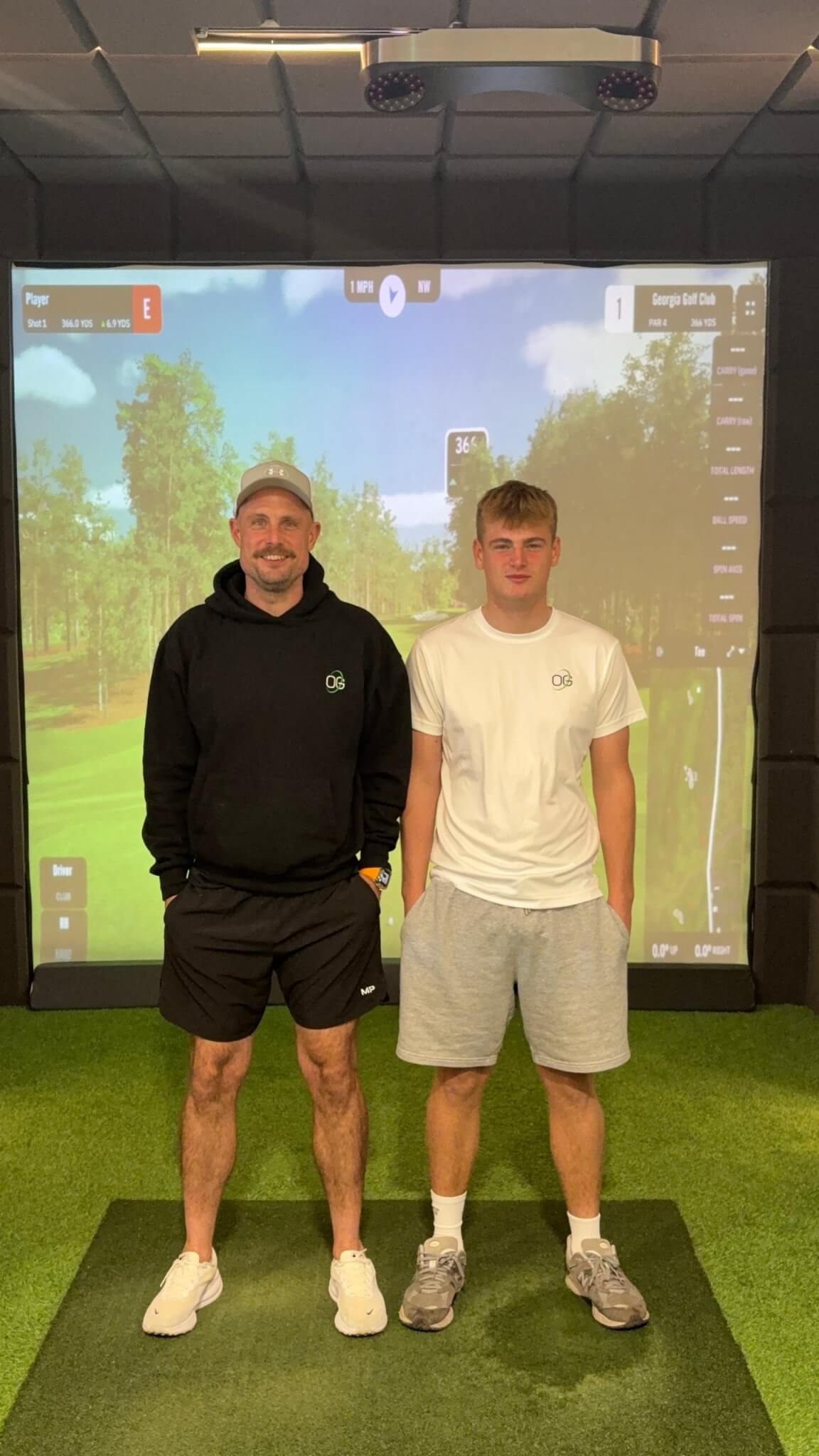 Dan O'Shaughnessy and his son Henry standing in front of a golf simulator screen at OSH Golf