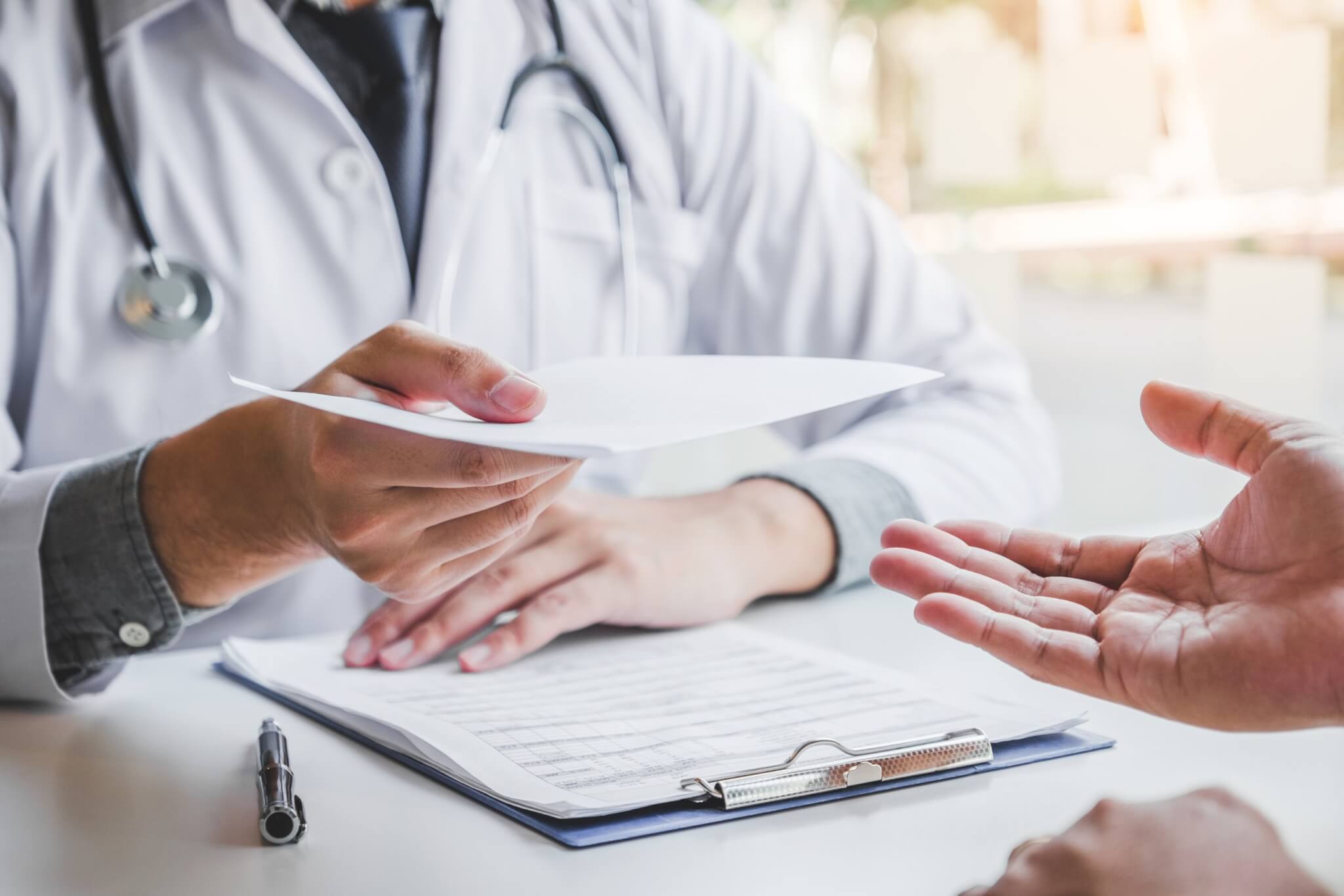 Doctor handing a prescription to a patient across a desk