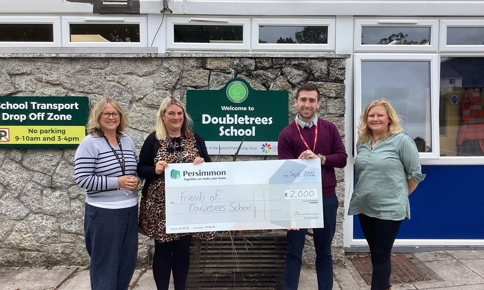 Staff from Doubletrees School and Persimmon Homes with a £2,000 cheque outside the school in St Blazey