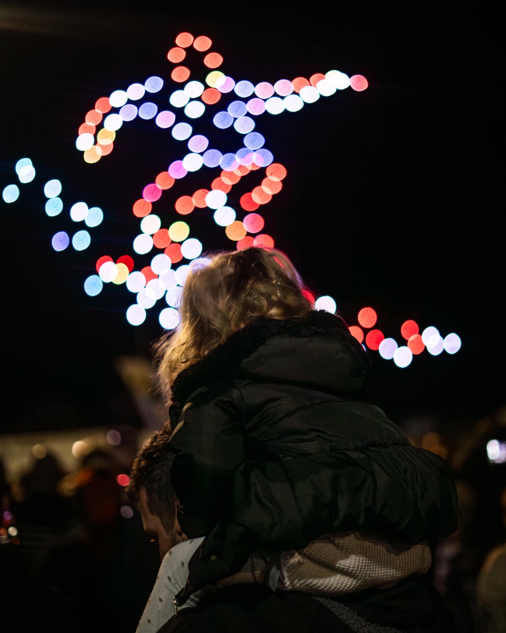 Drone formation lit in red and white above a crowd