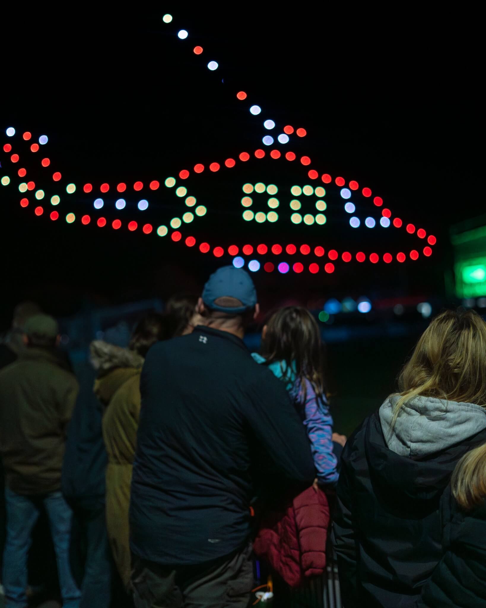 Drones forming a red helicopter shape above a crowd at night