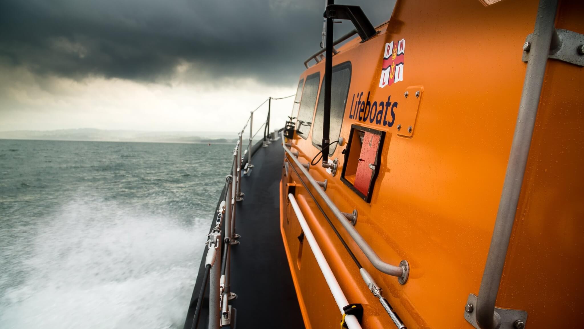 Orange RNLI Shannon class lifeboat at sea under dark storm clouds
