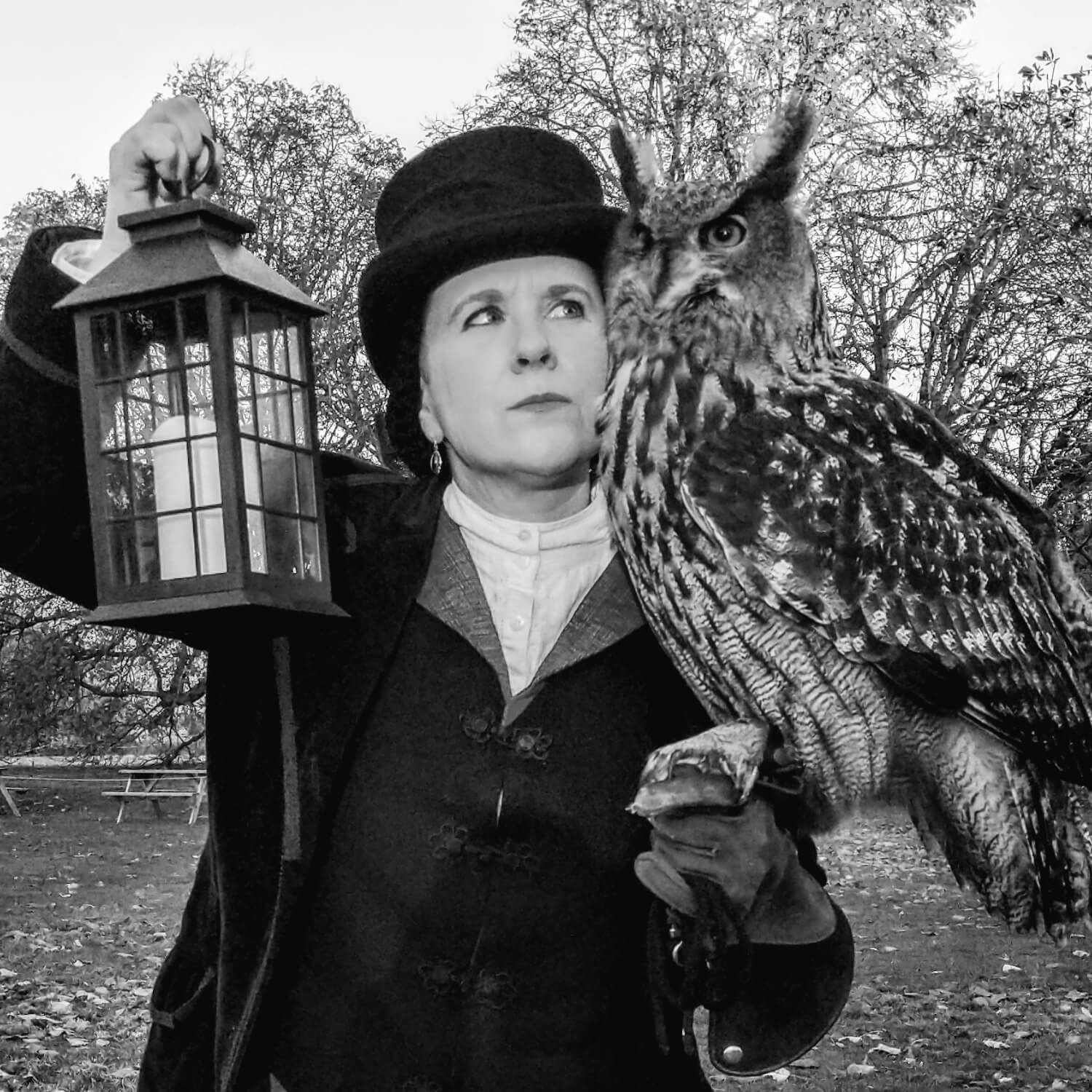 Falconer in Victorian dress holding a lantern with an eagle owl on her glove