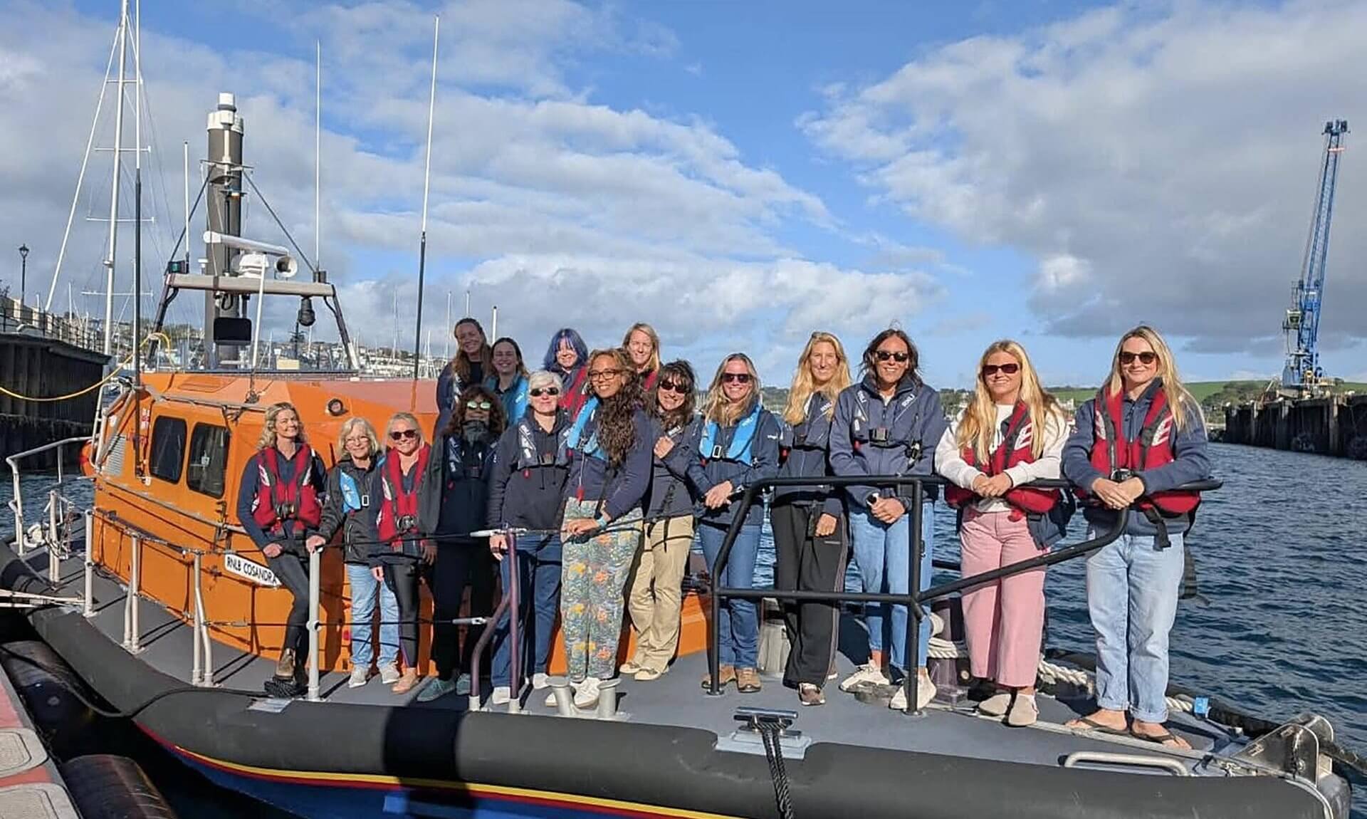 Women lifeboat crew standing on the bow of an RNLI lifeboat in Falmouth