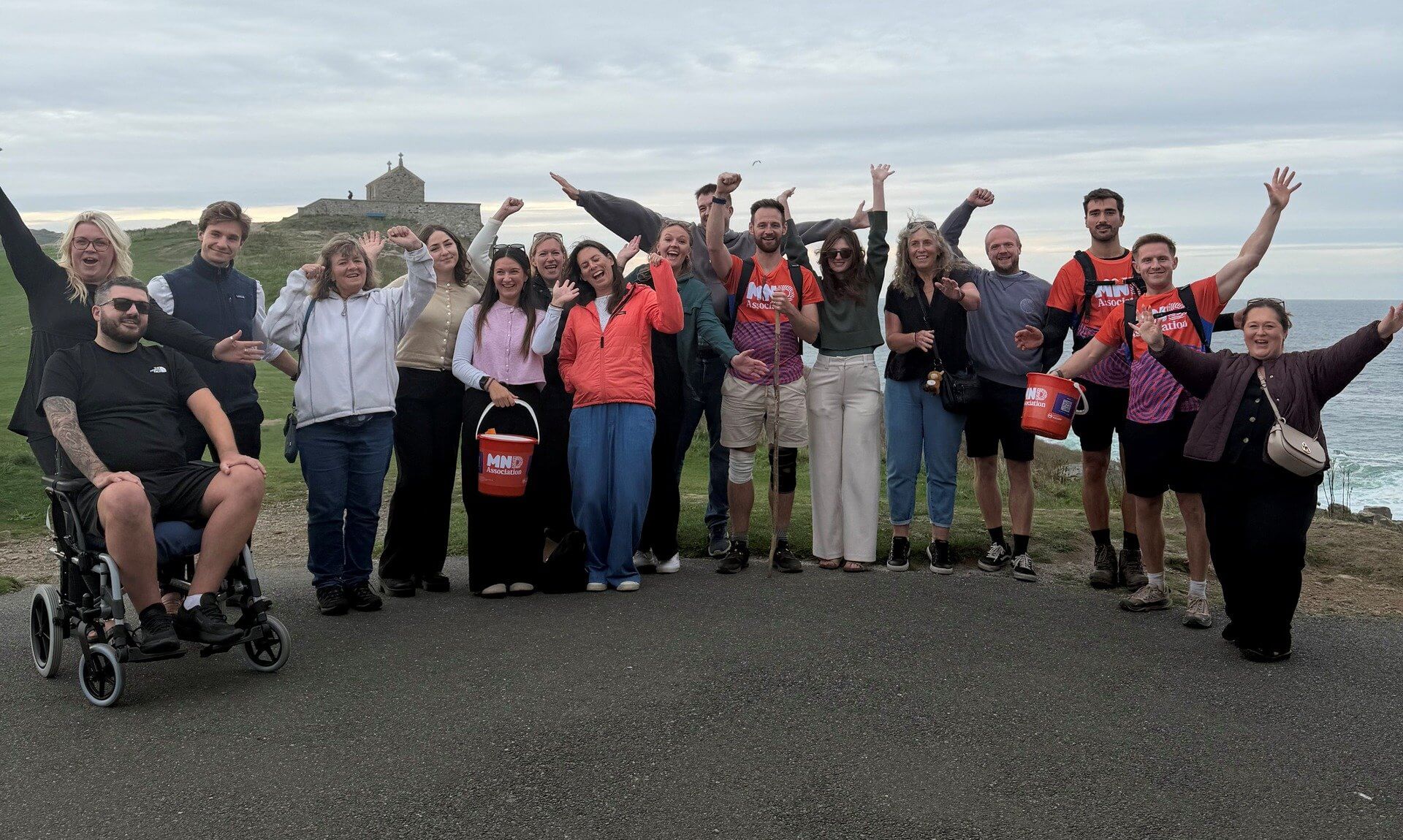 Walkers and supporters cheering on the coast at the end of The 100 Mile Hike