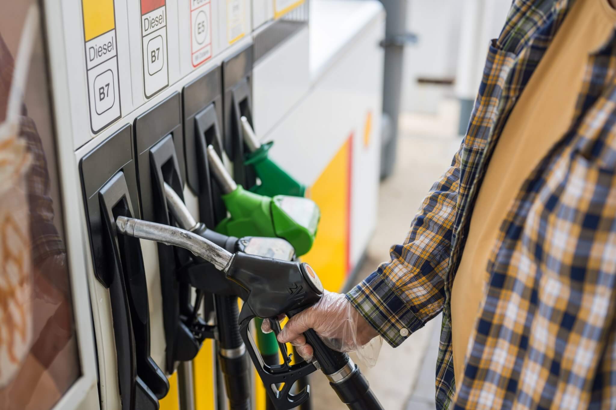 Driver holding a fuel pump nozzle at a petrol station forecourt