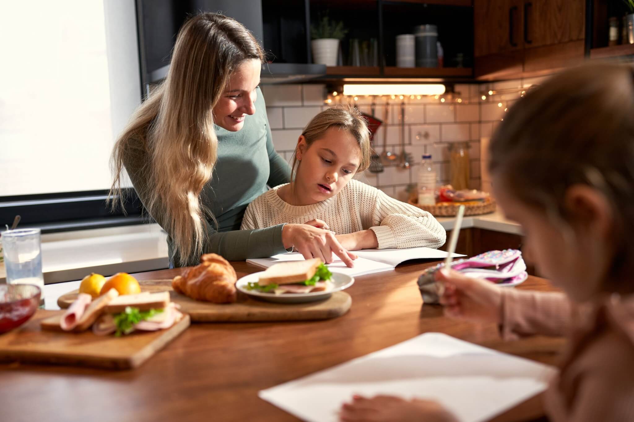 Woman helping a girl with homework at a kitchen table