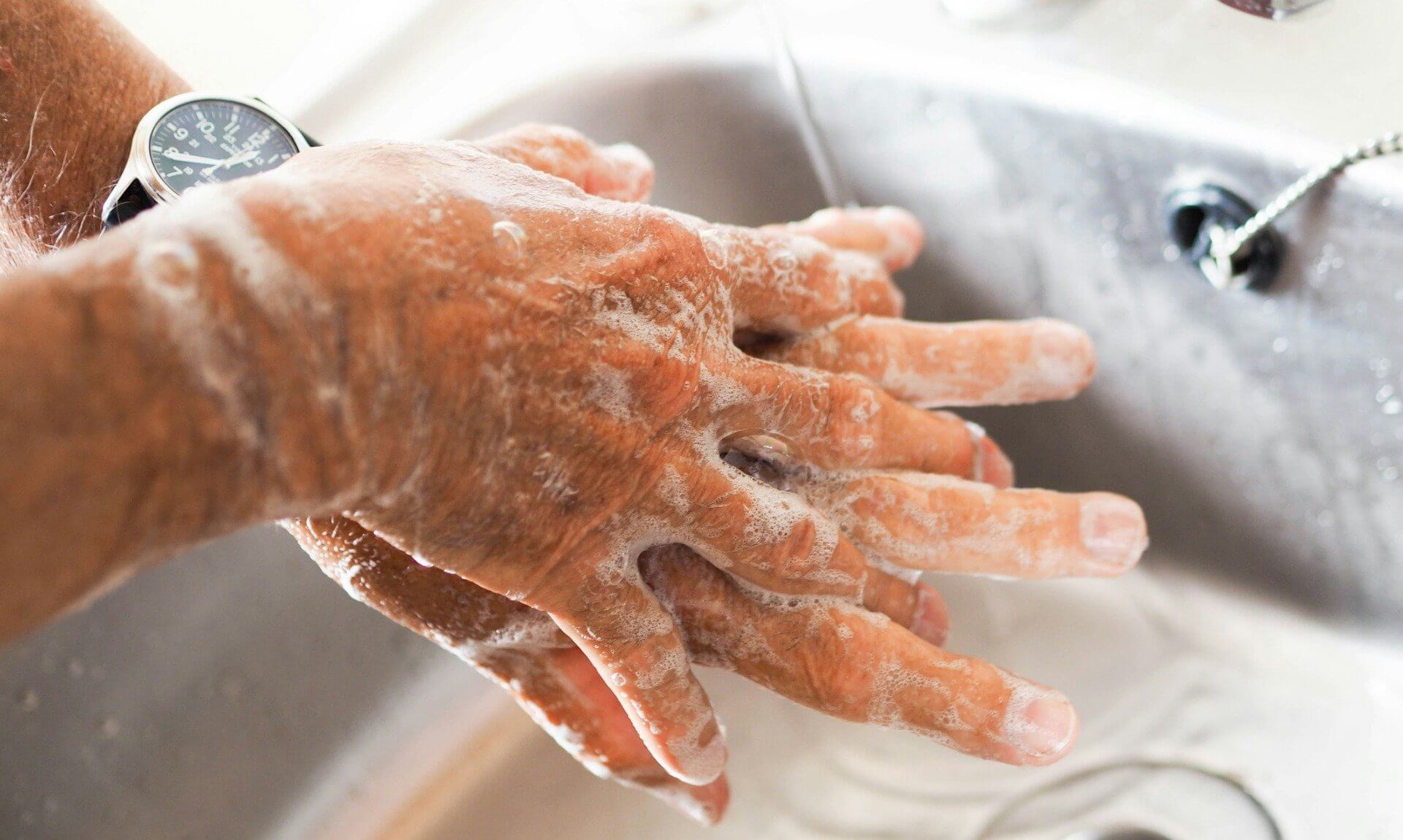 Soapy hands being washed under a running tap at a sink