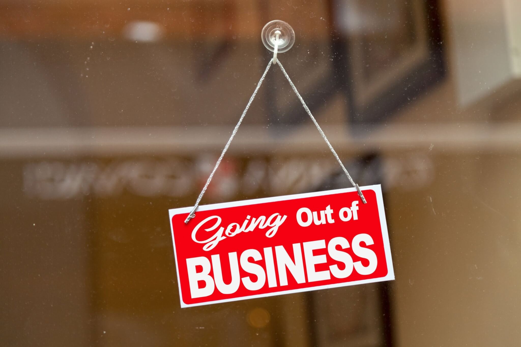 A red Going Out of Business sign hanging in a shop window