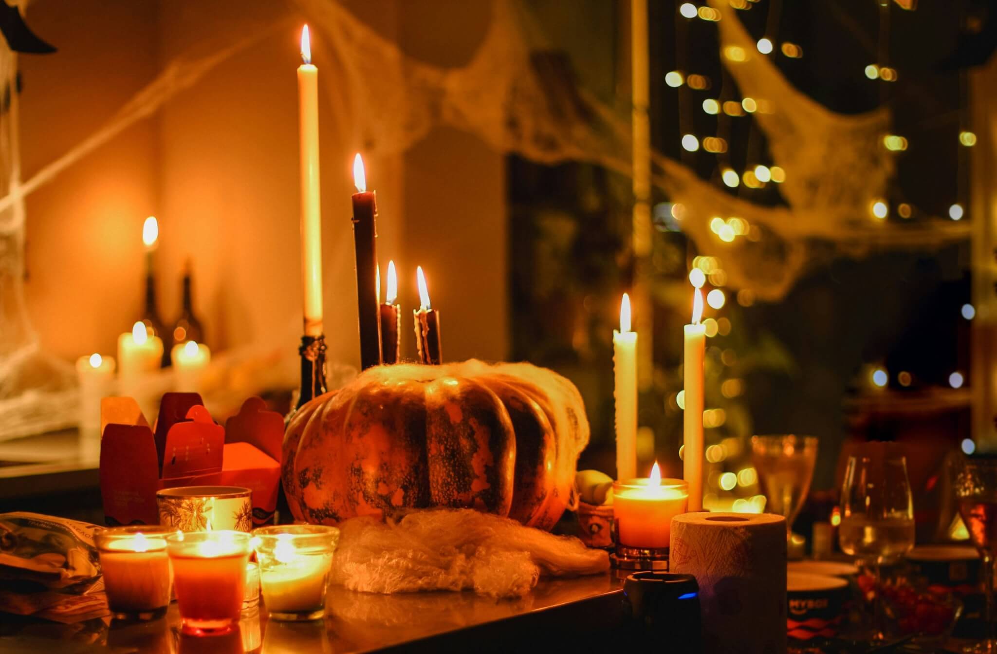 Lit candles around a pumpkin with fake cobwebs
