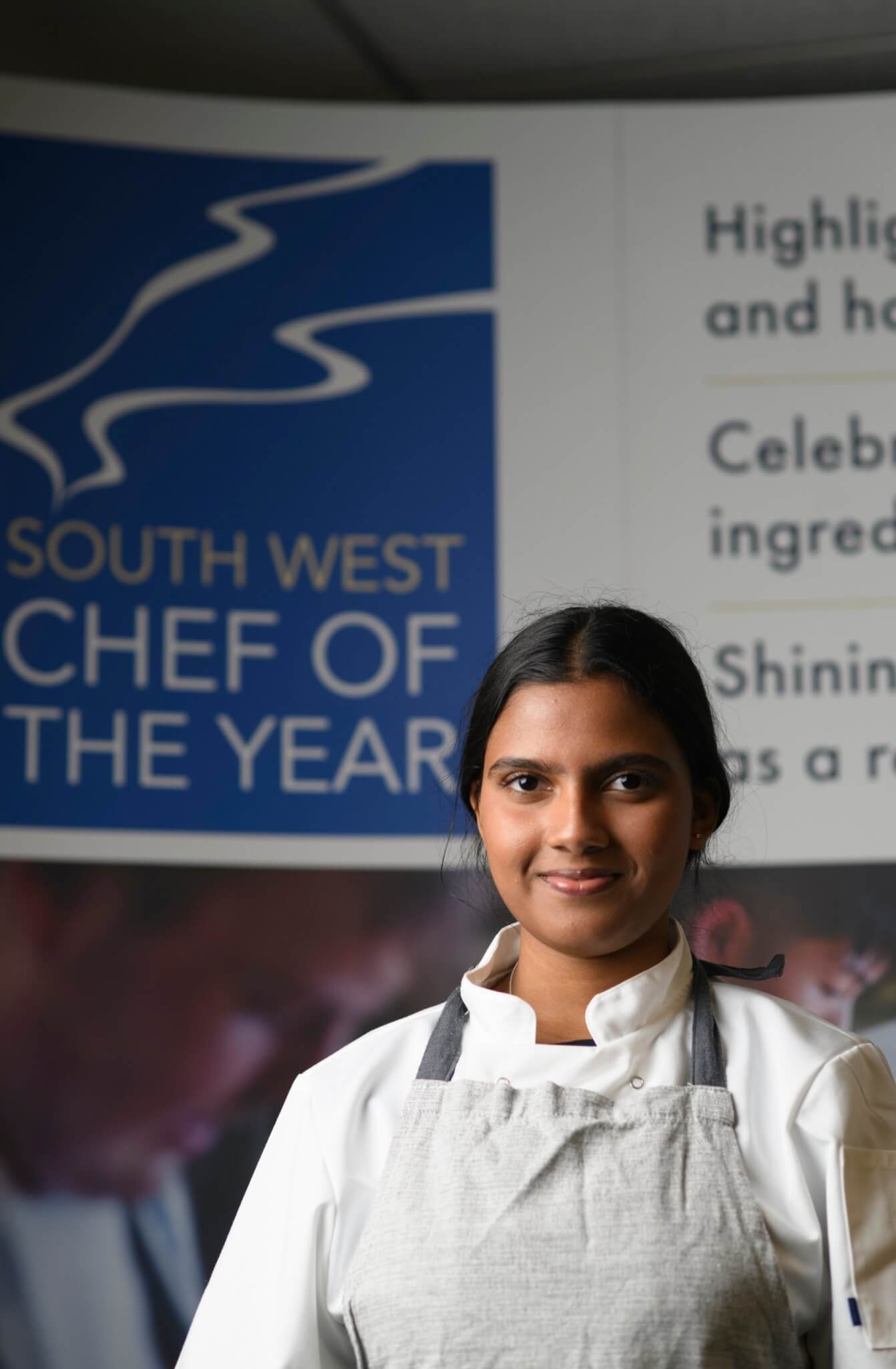 Hesali Galuge in chef's whites in front of a South West Chef of the Year banner
