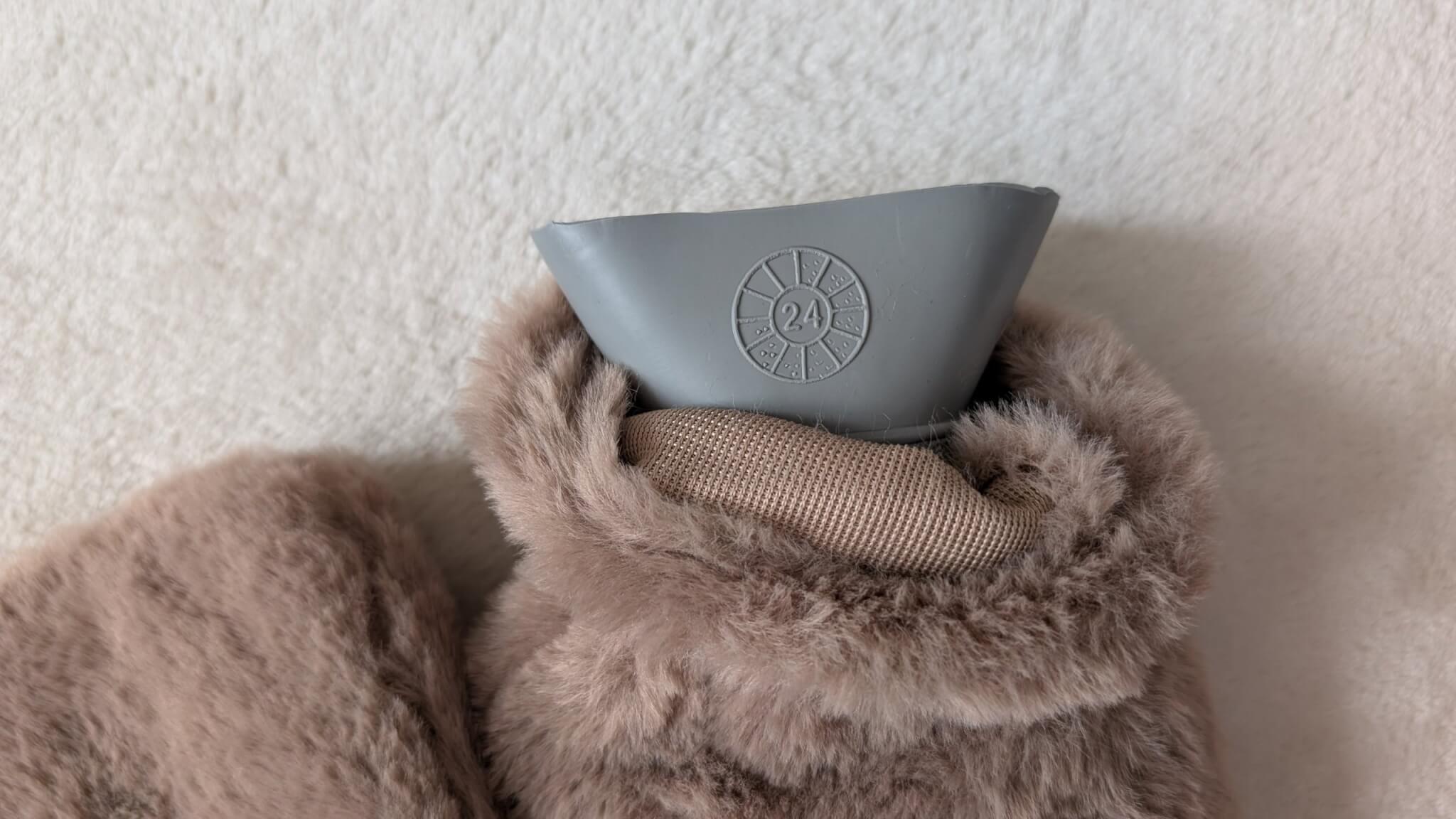 Daisy wheel date symbol on the neck of a hot water bottle in a faux fur cover