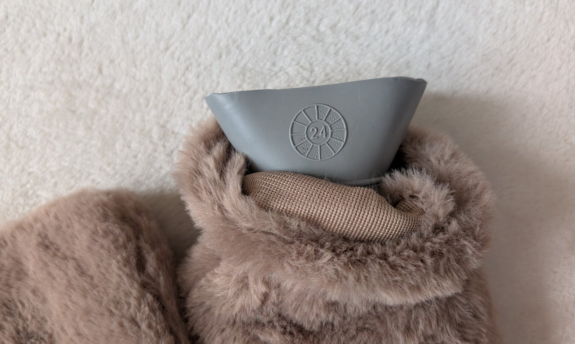 Daisy wheel date symbol on the neck of a hot water bottle in a faux fur cover