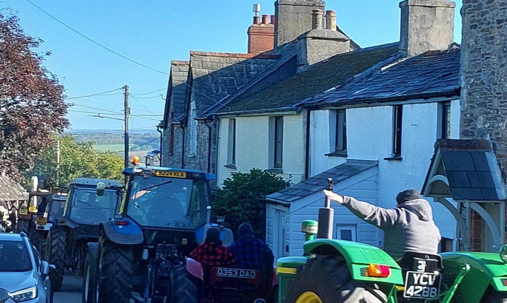 Tractors on the Bill Browning Memorial Tractor Run passing cottages near Lawhitton