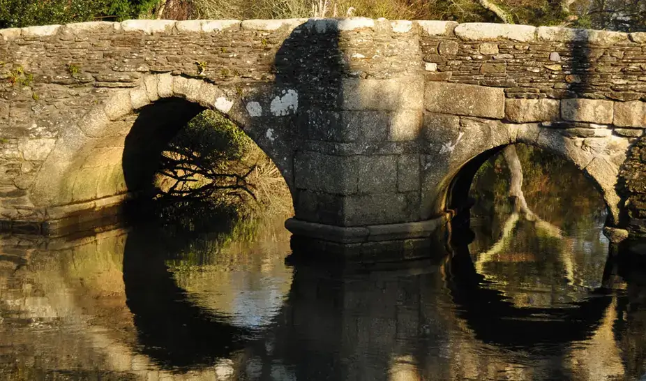Old stone bridge over the river at Lerryn reflected in the water