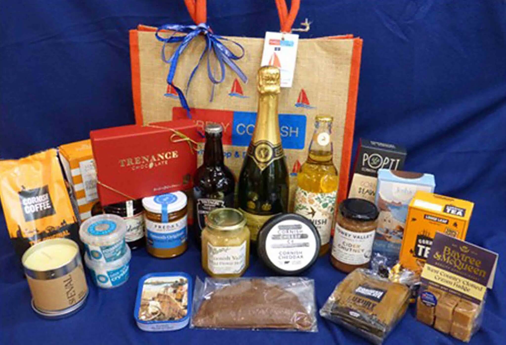 RNLI summer raffle hamper of Cornish food and drink in front of a Purely Cornish jute bag