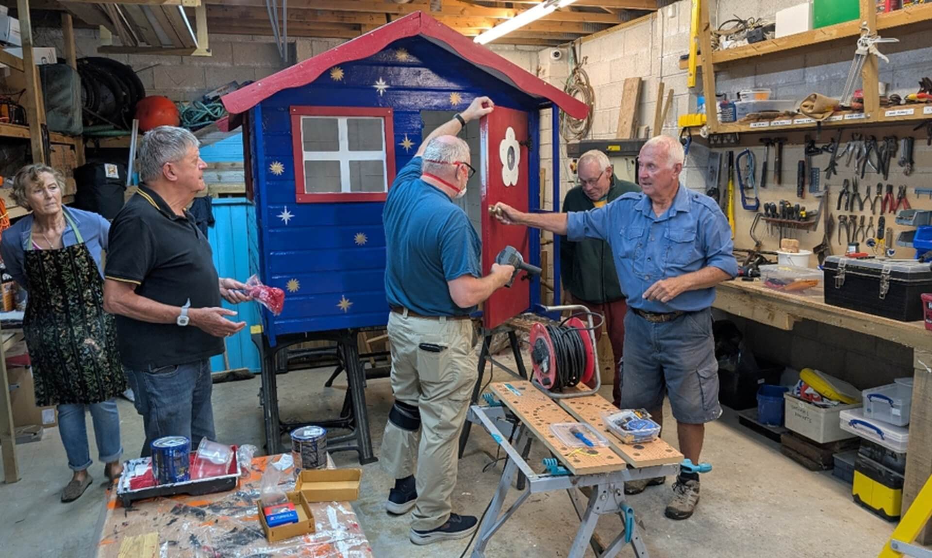 Looe Shedders volunteers working on a painted playhouse in their workshop