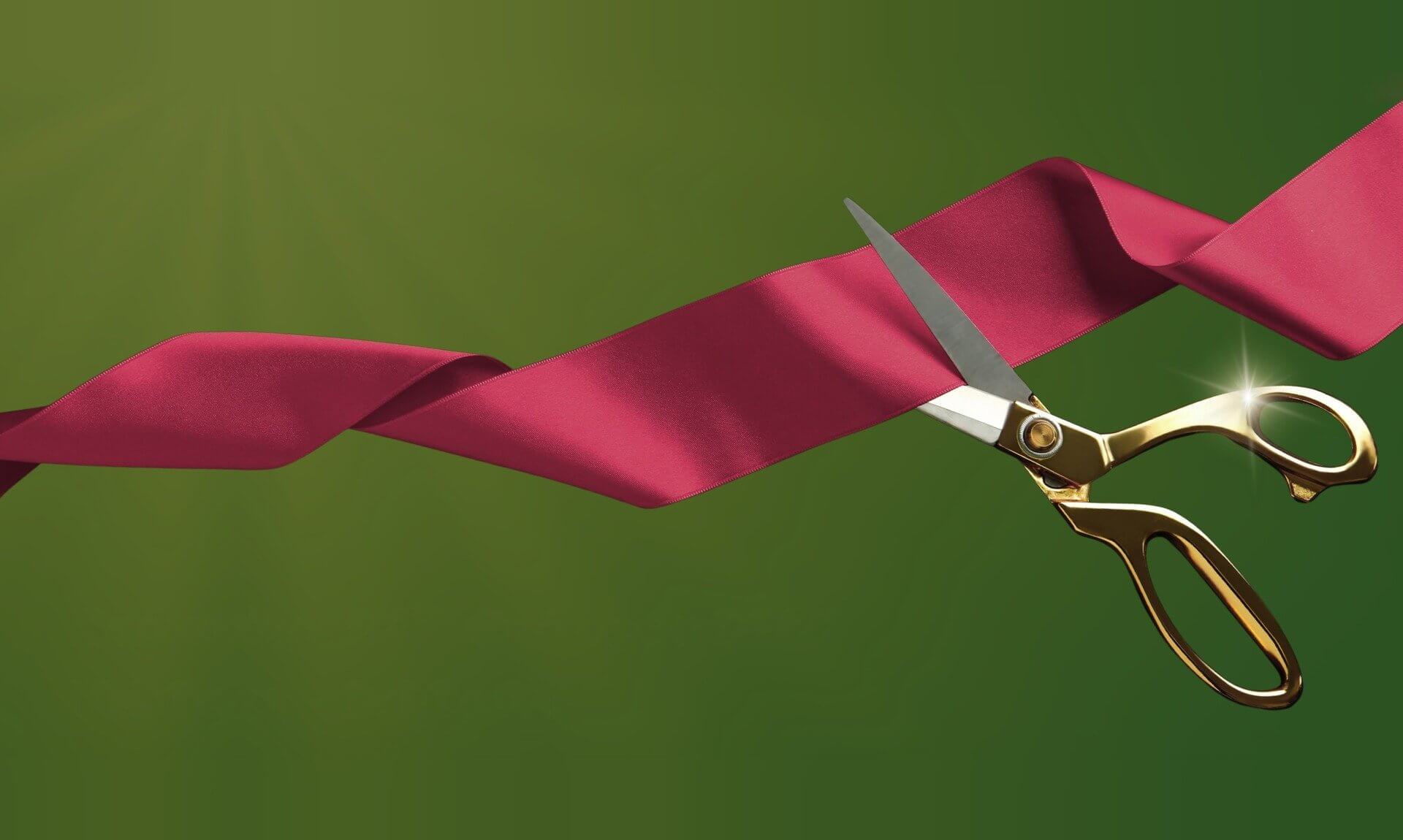 Red ribbon being cut with gold scissors for the Lowarth Holman opening