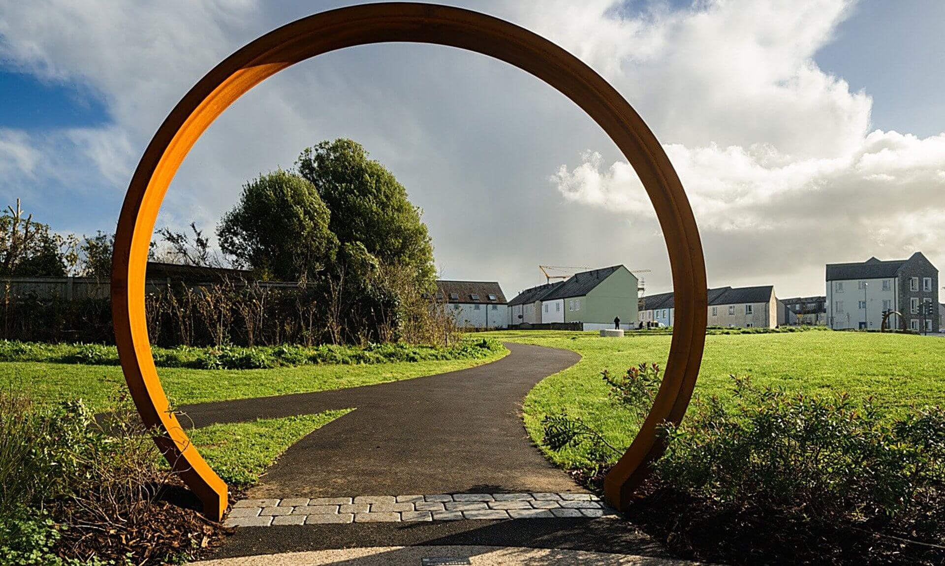 Weathering steel ring sculpture framing a path at Lowarth Holman, Camborne