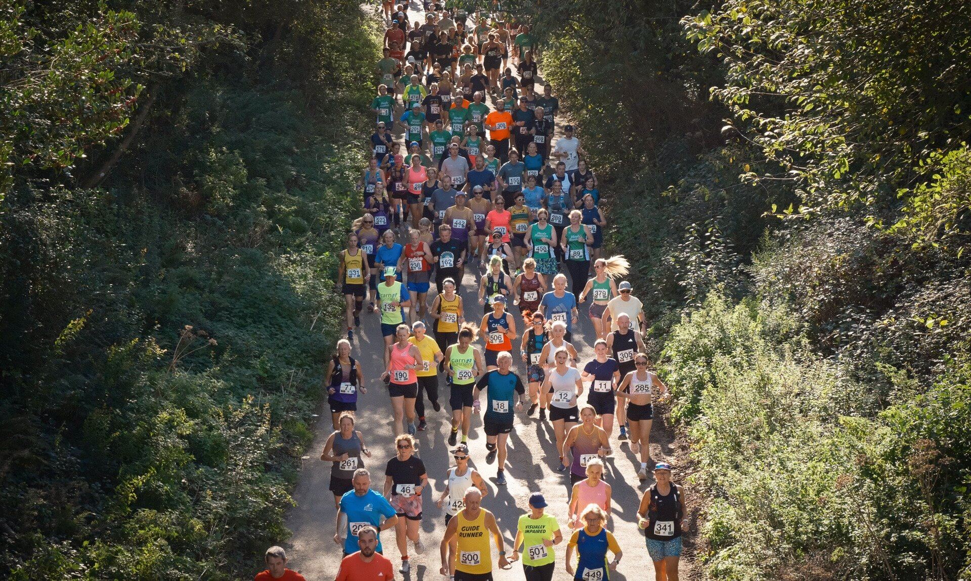 Runners fill a tree-lined lane at the start of the Marazion 10K